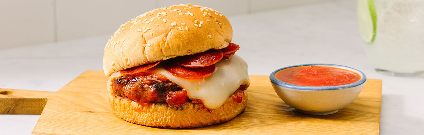 An image of prepared Easy Skillet Pizza Burgers made with Prego® Traditional Italian Sauce, ground beef, Parmesan, mozzarella, pepperoni and Pepperidge Farm® Farmhouse Hearty White Buns.