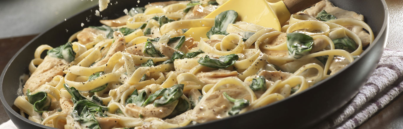 Simple Chicken Spinach Alfredo with Fettuccine with Prego® sauce cooking in a frying pan