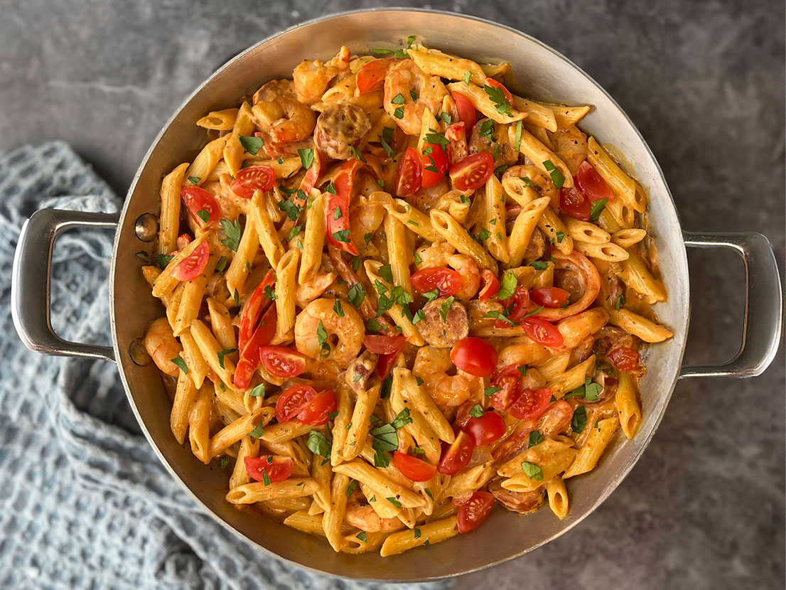 An image of Skillet Cajun Shrimp Alfredo made with Prego® Homestyle Alfredo Sauce, penne pasta, andouille sausage, bell pepper, shrimp, Cajun seasoning and tomatoes.