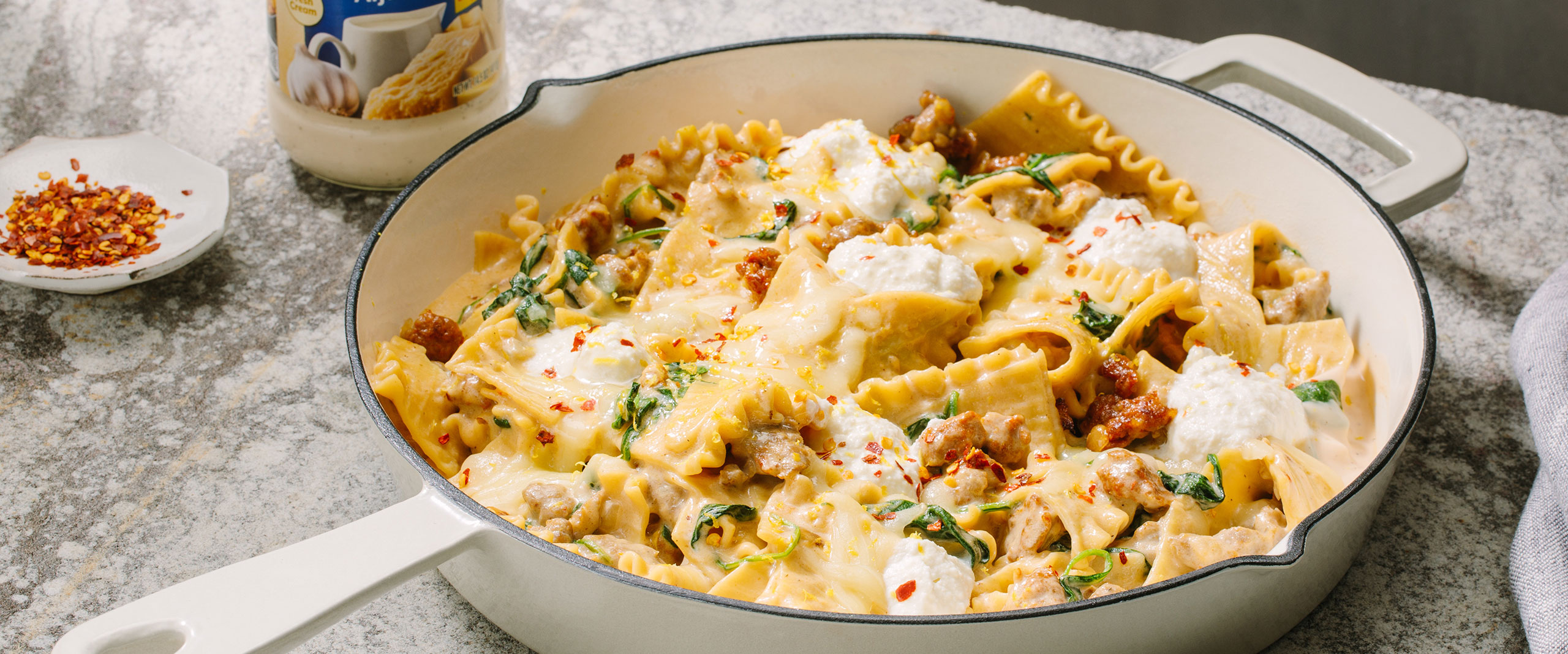 An image of prepared One Pot White Lasagna made with Prego® Homestyle Alfredo Sauce, Italian sausage, onion, lasagna noodles, baby spinach, mozzarella and ricotta cheese.