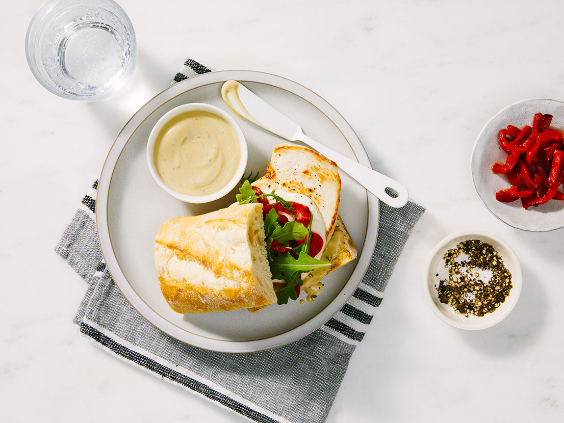 An image of prepared Creamy Pesto Chicken Sandwiches made with chicken, Prego® Creamy Basil Pesto Sauce, mozzarella, arugula and French baguette.