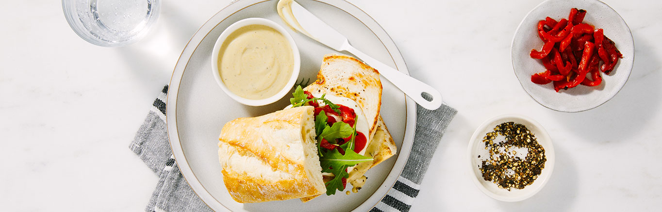 An image of prepared Creamy Pesto Chicken Sandwiches made with chicken, Prego® Creamy Basil Pesto Sauce, mozzarella, arugula and French baguette.